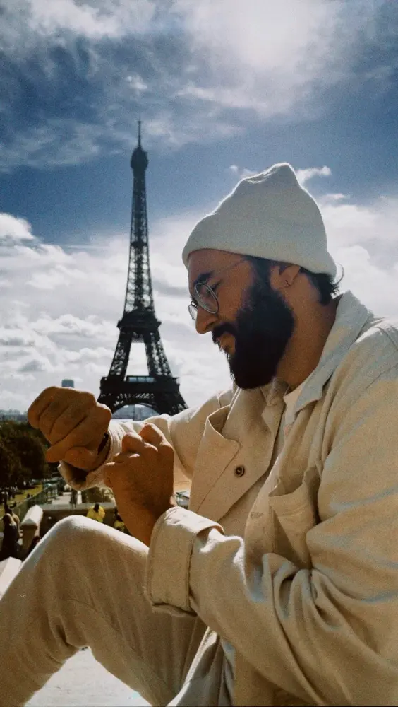 Evaldo sitting in front of the Eiffel Tower at night.